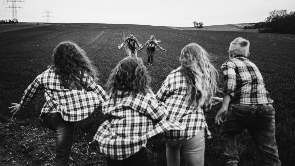 Kinder rennen über ein Feld auf die Eltern zu, Schwarzweiß-Familienshooting in Niederösterreich