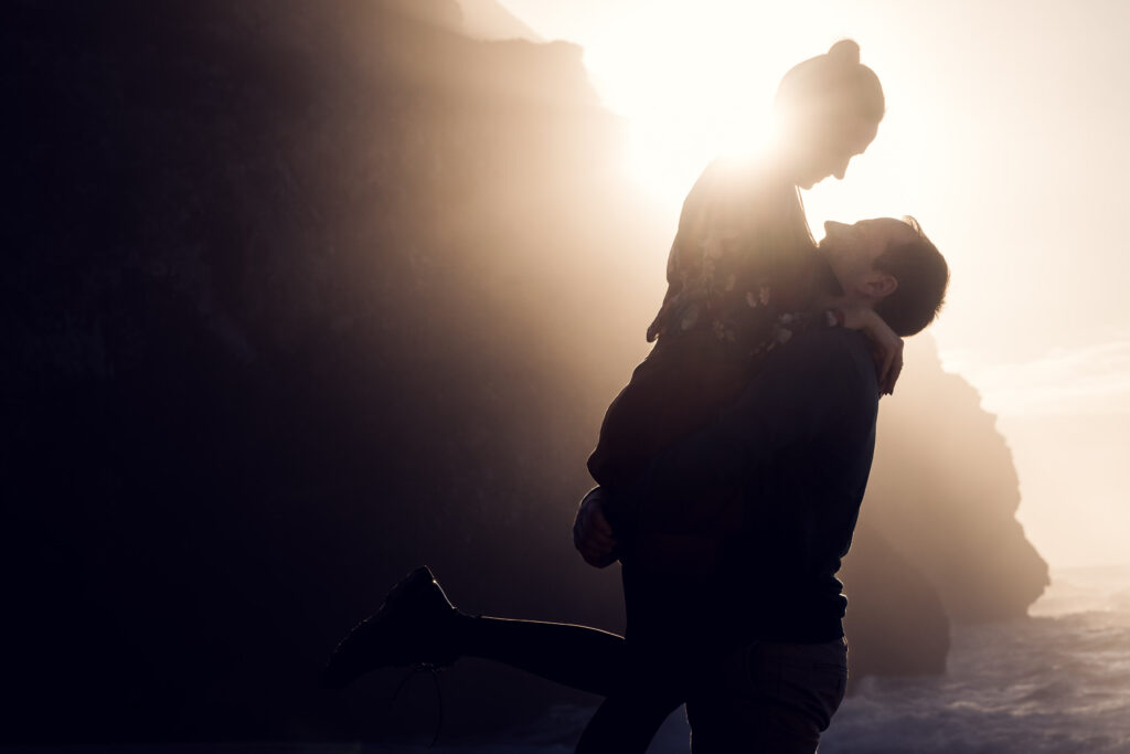 Mann hebt seine Partnerin hoch, Paarshooting als Silhouette im Gegenlicht der Abendsonne